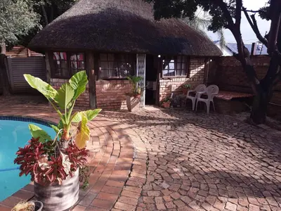 a house with a thatch roof and a pool at Ubuntu Guesthouse in Pretoria