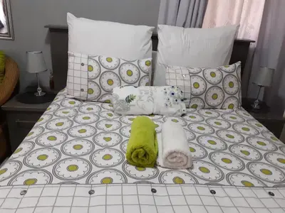 a bed with a green stuffed animal and pillows at Ubuntu Guesthouse in Pretoria