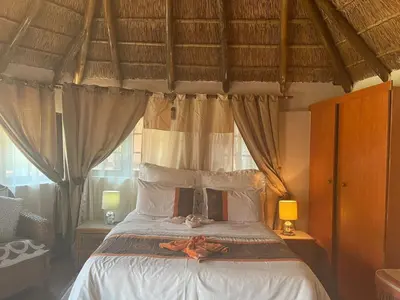 a bedroom with a bed with white sheets and curtains at Ubuntu Guesthouse in Pretoria