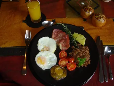 a plate of food with eggs and tomatoes on a table at Selati 103 Guest Cottages in Malelane