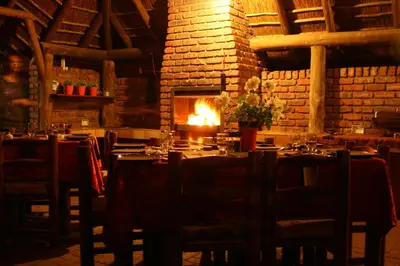 a dining room with a table and a fireplace at Selati 103 Guest Cottages in Malelane