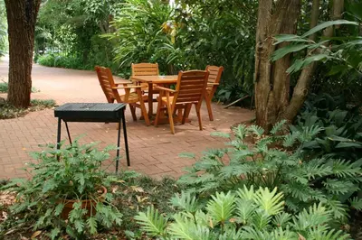 a wooden table and chairs in a garden at Selati 103 Guest Cottages in Malelane
