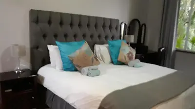 a bed with blue and white pillows on it at Selati 103 Guest Cottages in Malelane
