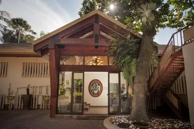a house with glass doors and a tree at Tamboti Lodge Guest House in Tzaneen