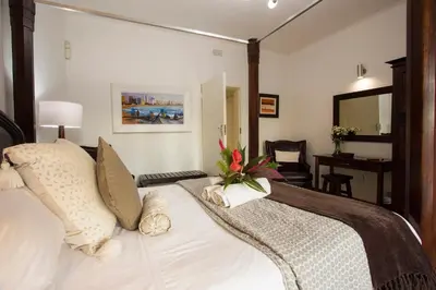 a bedroom with a bed and a desk at Tamboti Lodge Guest House in Tzaneen