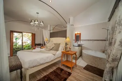 a bedroom with a large bed and a bath tub at Tamboti Lodge Guest House in Tzaneen