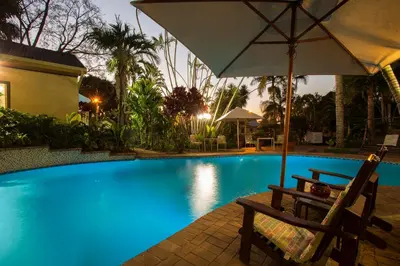 a chair with an umbrella next to a swimming pool at Tamboti Lodge Guest House in Tzaneen