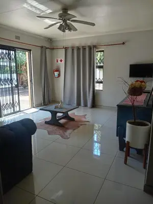 a living room with a table on a tiled floor at Tokelo Guesthouse Emalahleni in Witbank