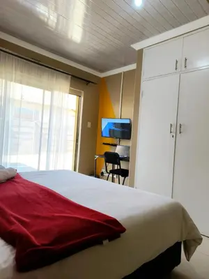 a bedroom with a large bed and a tv at Tokelo Guesthouse Emalahleni in Witbank