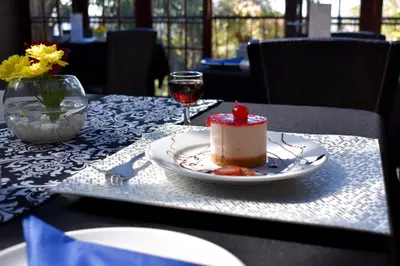 a piece of cake on a table with a glass of wine at Waterfalls Boutique Hotel in Pretoria
