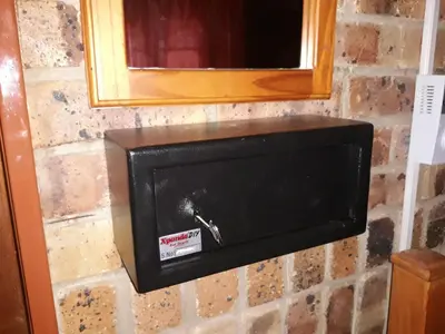 a fire safe on a brick wall with a mirror at Little Bush Baby in Marloth Park