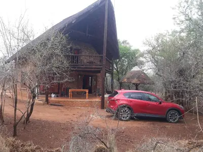 a red car parked in front of a house at Little Bush Baby in Marloth Park