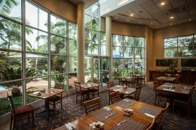 a restaurant with tables and chairs and large windows at StayEasy Pretoria in Pretoria
