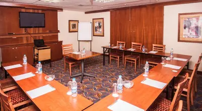 a conference room with wooden tables and chairs and a screen at StayEasy Pretoria in Pretoria