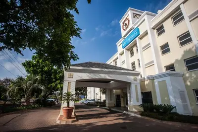 a white building with a clock tower on top at StayEasy Pretoria in Pretoria