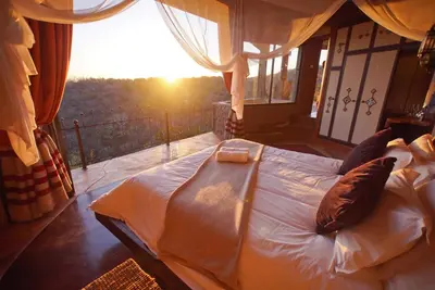 a bed in a room with the sun shining through a window at Leopards Rock Bush Boutique in Bela-Bela