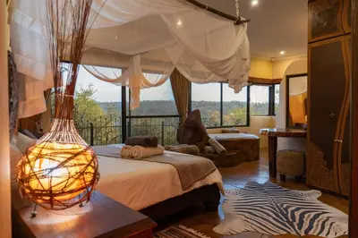 a bedroom with a bed and a large window at Leopards Rock Bush Boutique in Bela-Bela