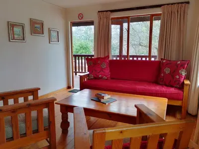 a living room with a red couch and a table at Zongororo Mountain Lodge in Waterval-Onder