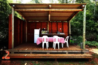 a table and chairs on a wooden deck with a kitchen at Zongororo Mountain Lodge in Waterval-Onder