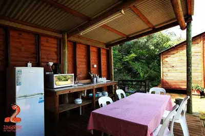 an outdoor kitchen with a table and a refrigerator at Zongororo Mountain Lodge in Waterval-Onder