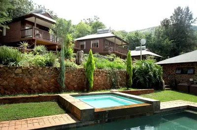 a backyard with a swimming pool and a house at Zongororo Mountain Lodge in Waterval-Onder