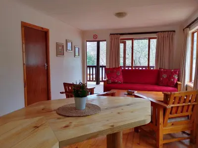 a living room with a table and a red couch at Zongororo Mountain Lodge in Waterval-Onder
