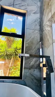a bathroom with a bath tub and a window at Sunrise Boutique Hotel in Witbank