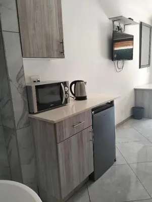 a small kitchen with a microwave and a sink at Sunrise Boutique Hotel in Witbank