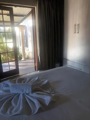 a bed in a bedroom with an open door at Sunrise Boutique Hotel in Witbank
