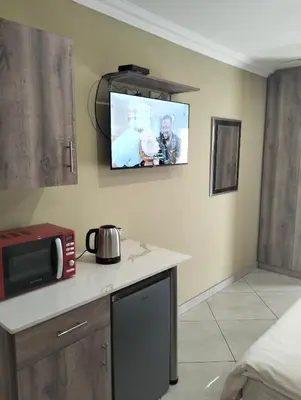 a kitchen with a microwave and a tv on the wall at Sunrise Boutique Hotel in Witbank