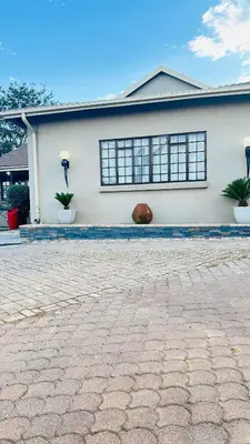 a white house with two windows and a brick driveway at Sunrise Boutique Hotel in Witbank