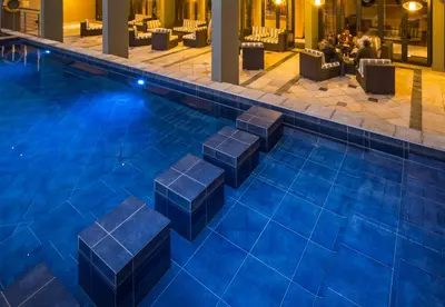 a pool in a hotel with people sitting in chairs at Premier Hotel O.R. Tambo in Kempton Park