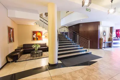 a lobby with a couch and a spiral staircase at Premier Hotel O.R. Tambo in Kempton Park