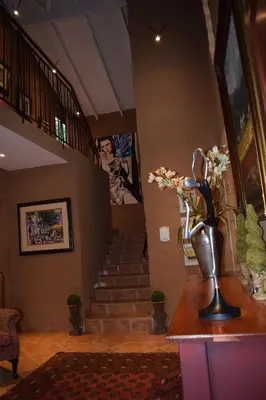 a lobby with a staircase and a vase of flowers on a table at Chateau Vue Guesthouse in Pretoria