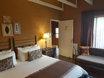 a bedroom with a bed and a couch and a window at Chateau Vue Guesthouse in Pretoria
