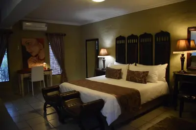 a hotel room with a large bed and a desk at Chateau Vue Guesthouse in Pretoria