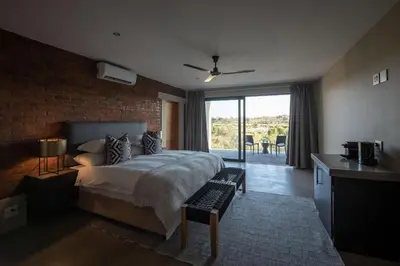a bedroom with a bed with a brick wall at Tamboti River Lodge in Hectorspruit