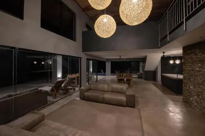 a living room with a couch and chairs and lights at Tamboti River Lodge in Hectorspruit