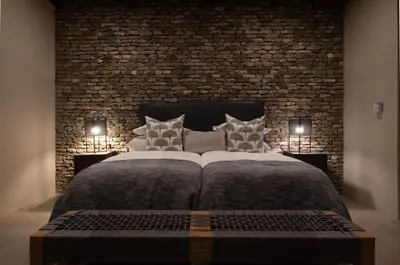 a bedroom with a large bed with a brick wall at Tamboti River Lodge in Hectorspruit