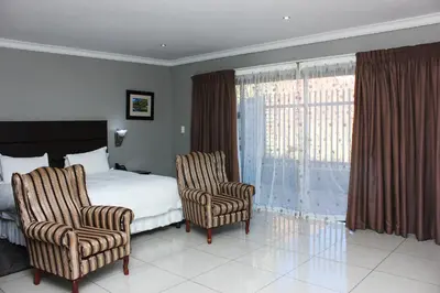 a hotel room with a bed and two chairs at Vahlavi Lodge in Giyani