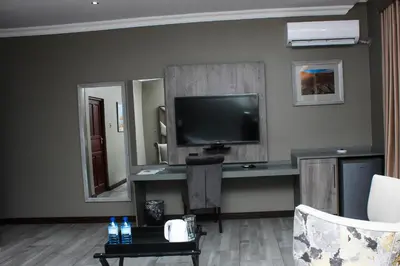 a living room with a television and a desk with a tv at Vahlavi Lodge in Giyani