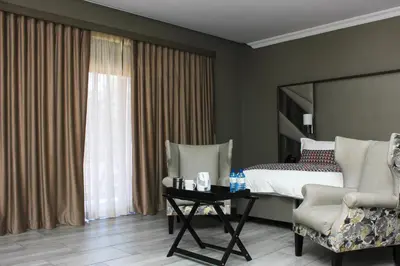 a bedroom with a bed and a table and chairs at Vahlavi Lodge in Giyani