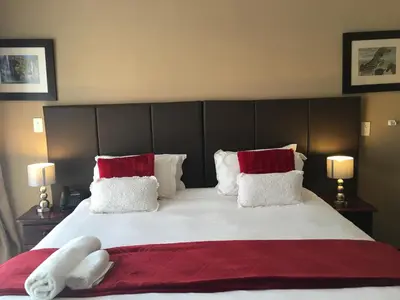 a bedroom with a large bed with red and white pillows at Vahlavi Lodge in Giyani
