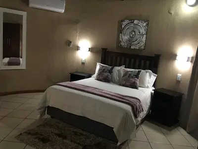 a bedroom with a large bed with two night stands at Vahlavi Lodge in Giyani