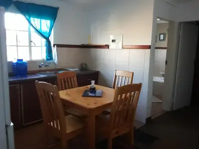 a wooden table and chairs in a kitchen with a sink at Dullstroom on the Dam in Dullstroom