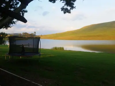 a trampoline in the grass next to a lake at Dullstroom on the Dam in Dullstroom