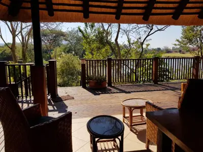 a wooden deck with chairs and tables on it at Kruger Park Lodge ITR01 3 Bedroom in Hazyview