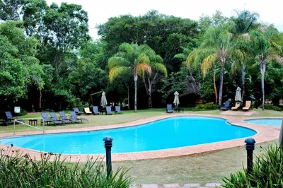 a swimming pool in a park with palm trees at Kruger Park Lodge ITR01 3 Bedroom in Hazyview