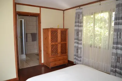 a bedroom with a bed and a cabinet and a window at Log Cabin & Settlers Village in Graskop