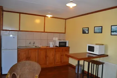 a kitchen with a table and a white microwave at Log Cabin & Settlers Village in Graskop